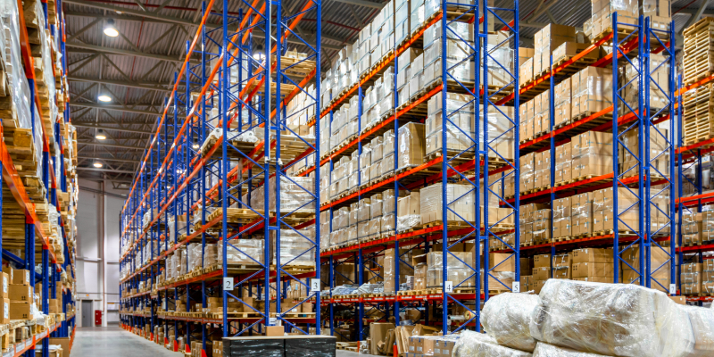 Interior of a warehouse storage of retail shop with pallet tracks illustrates the difference between heavy duty pallet racking and Very Narrow Aisle racking.
